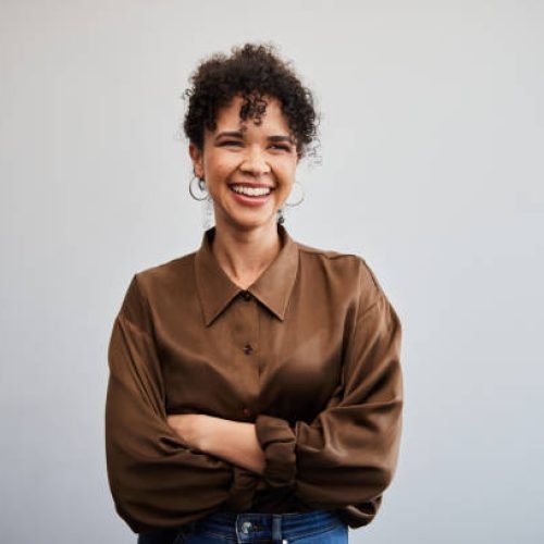 istockphoto-2099403180-612×612 Portrait of a young businesswoman smiling while standing with her arms crossed in front of a white wall in an office