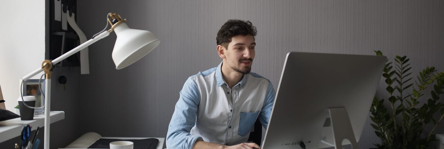 Young male designer using graphics tablet while working with computer at studio or office.